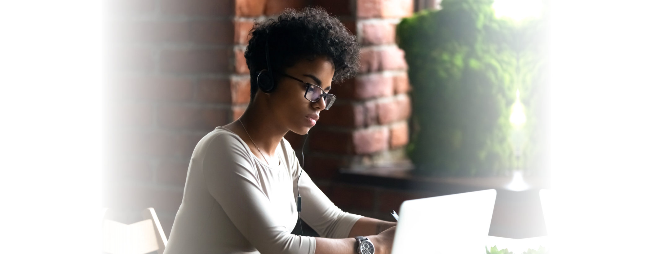 Focused African American woman wearing headphones using laptop